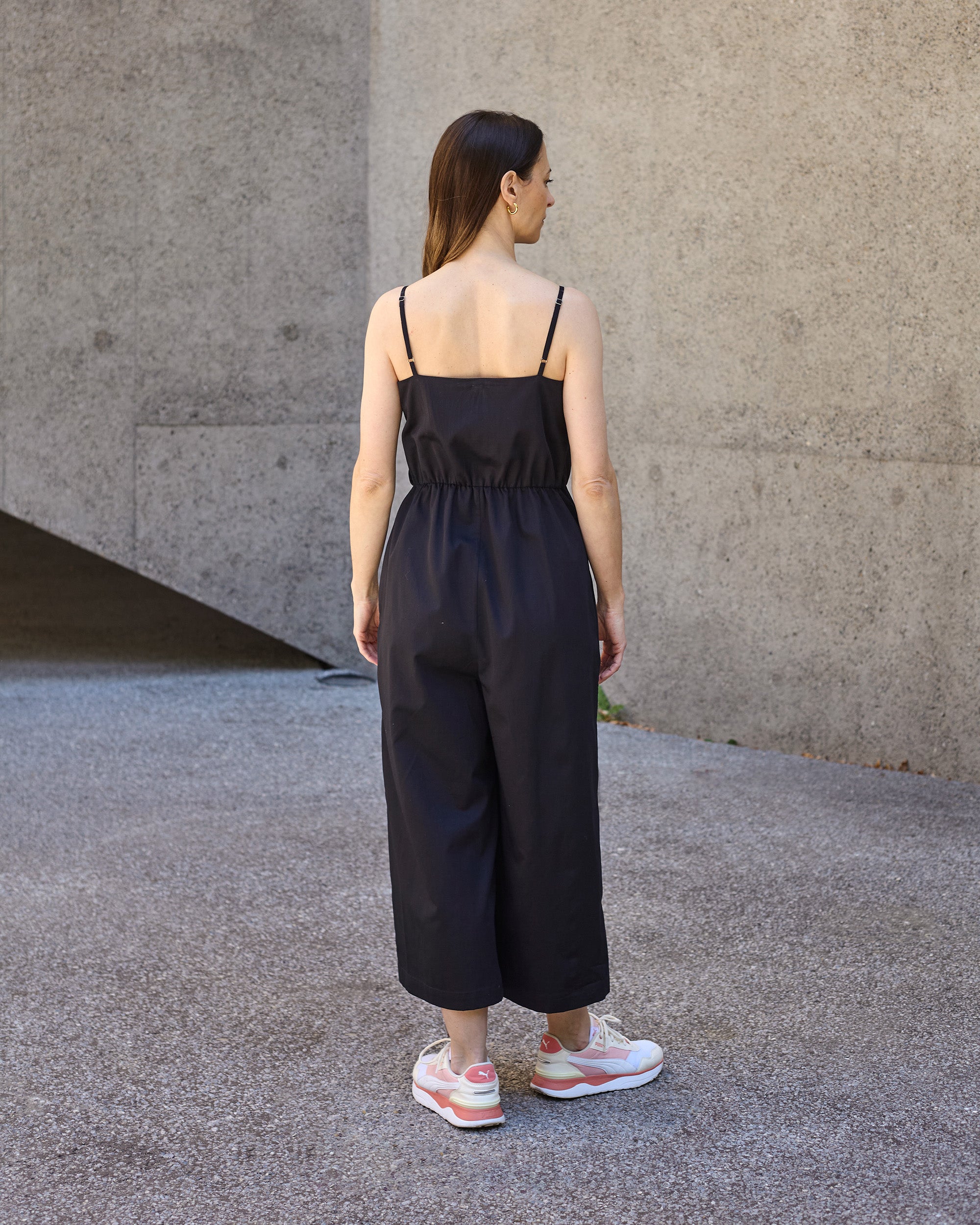 Back view of petite black wrap jumpsuit with adjustable shoulder straps.