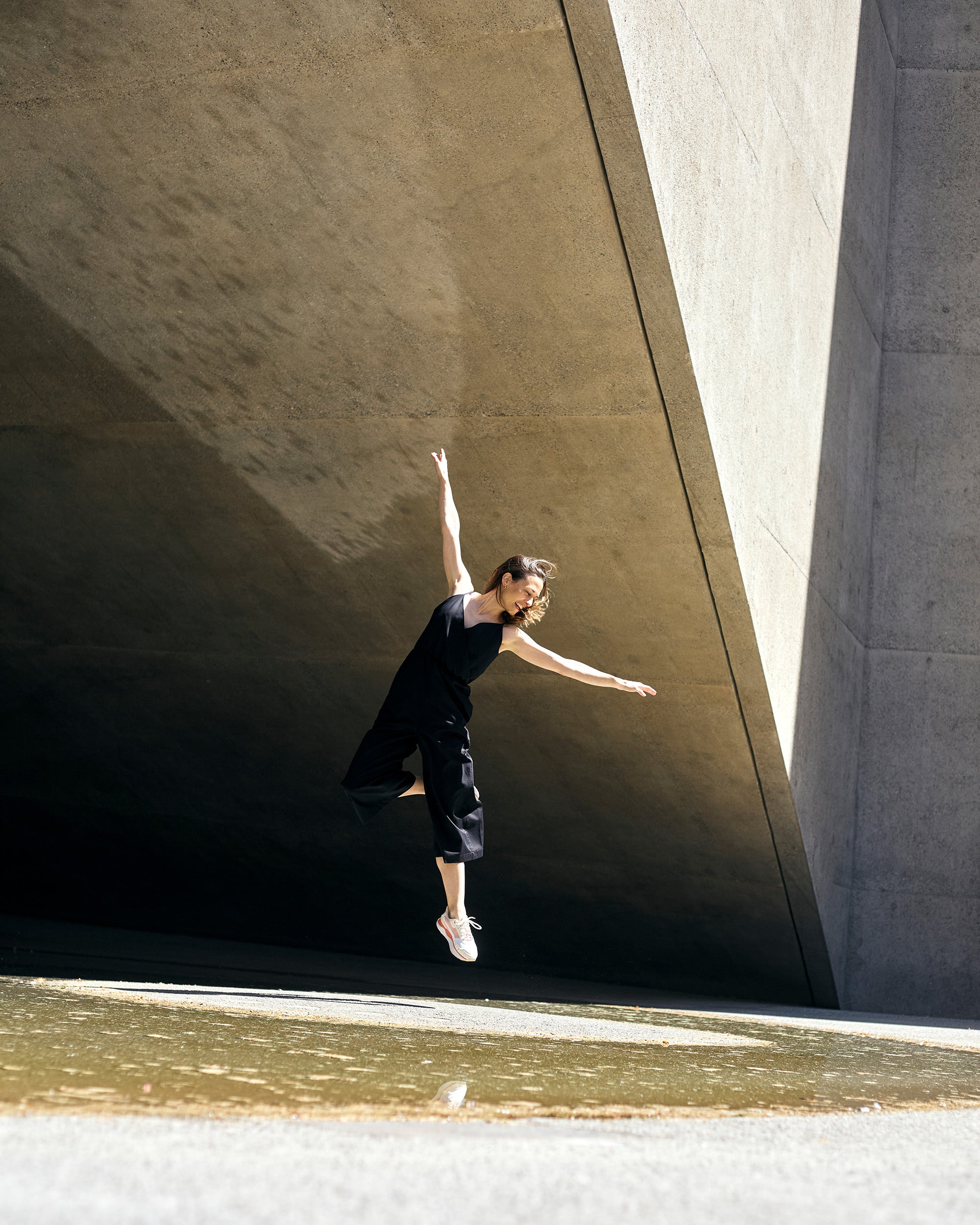 Model wearing petite black wrap jumpsuit captured in motion.