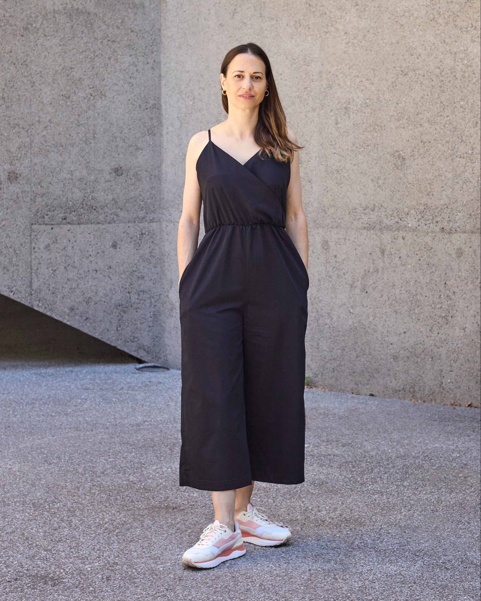 Model wearing petite black wrap jumpsuit with cropped wide-leg silhouette.