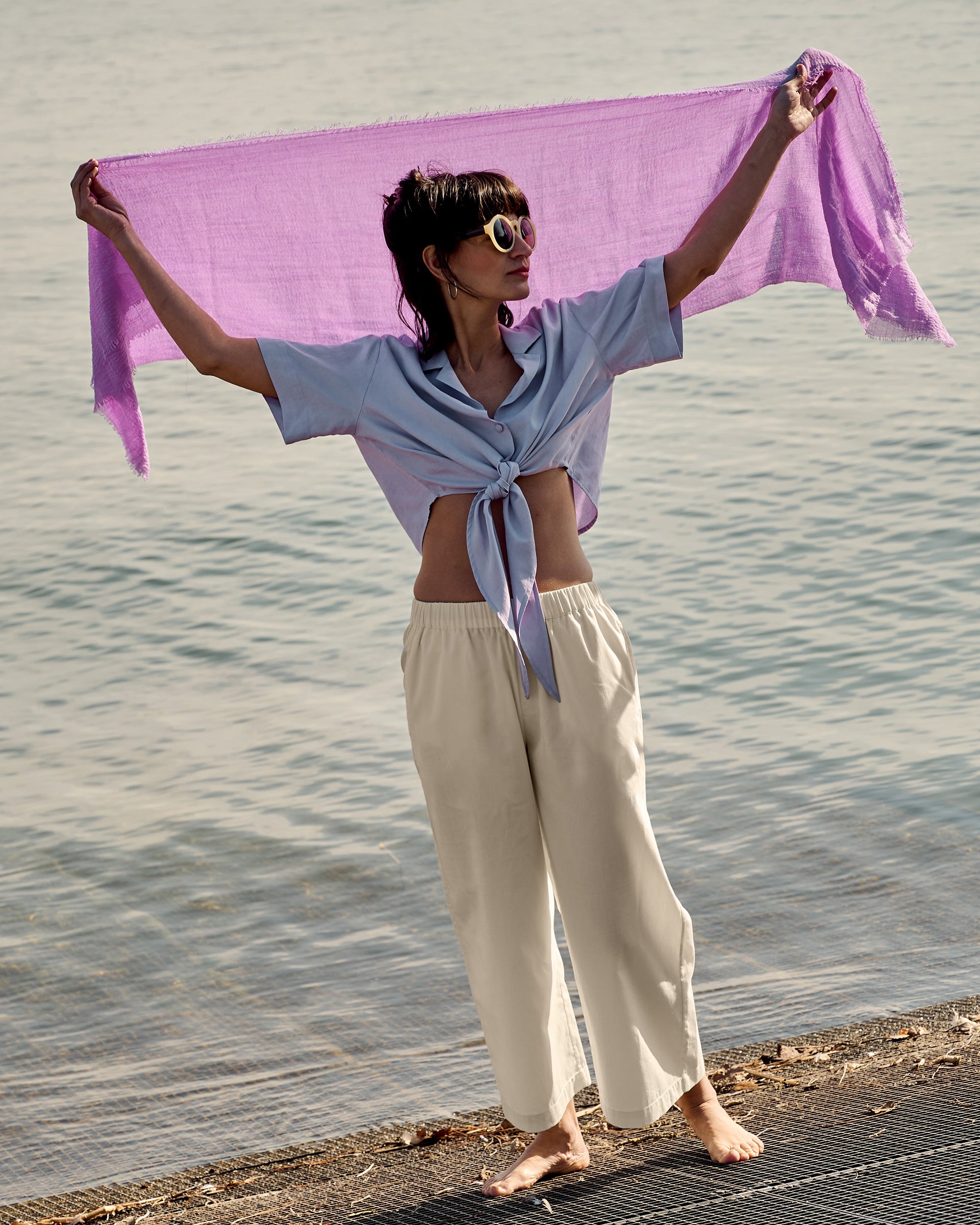 Petite model wearing the Wide Leg Trouser Ecru with a lilac wrap blouse at the lakeside.