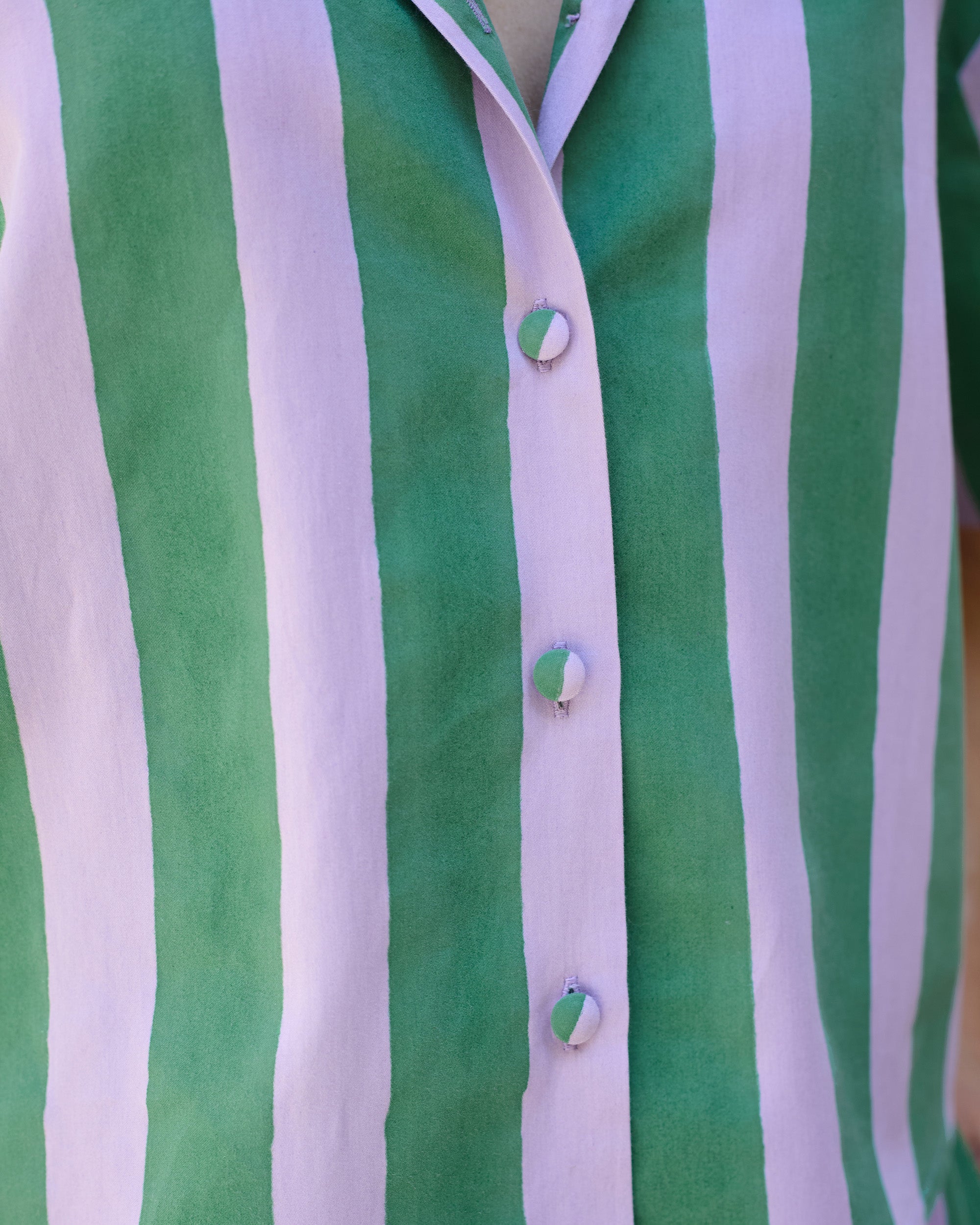 Close-up of the button placket on a petite striped blockprint blouse in green and lilac stripes.