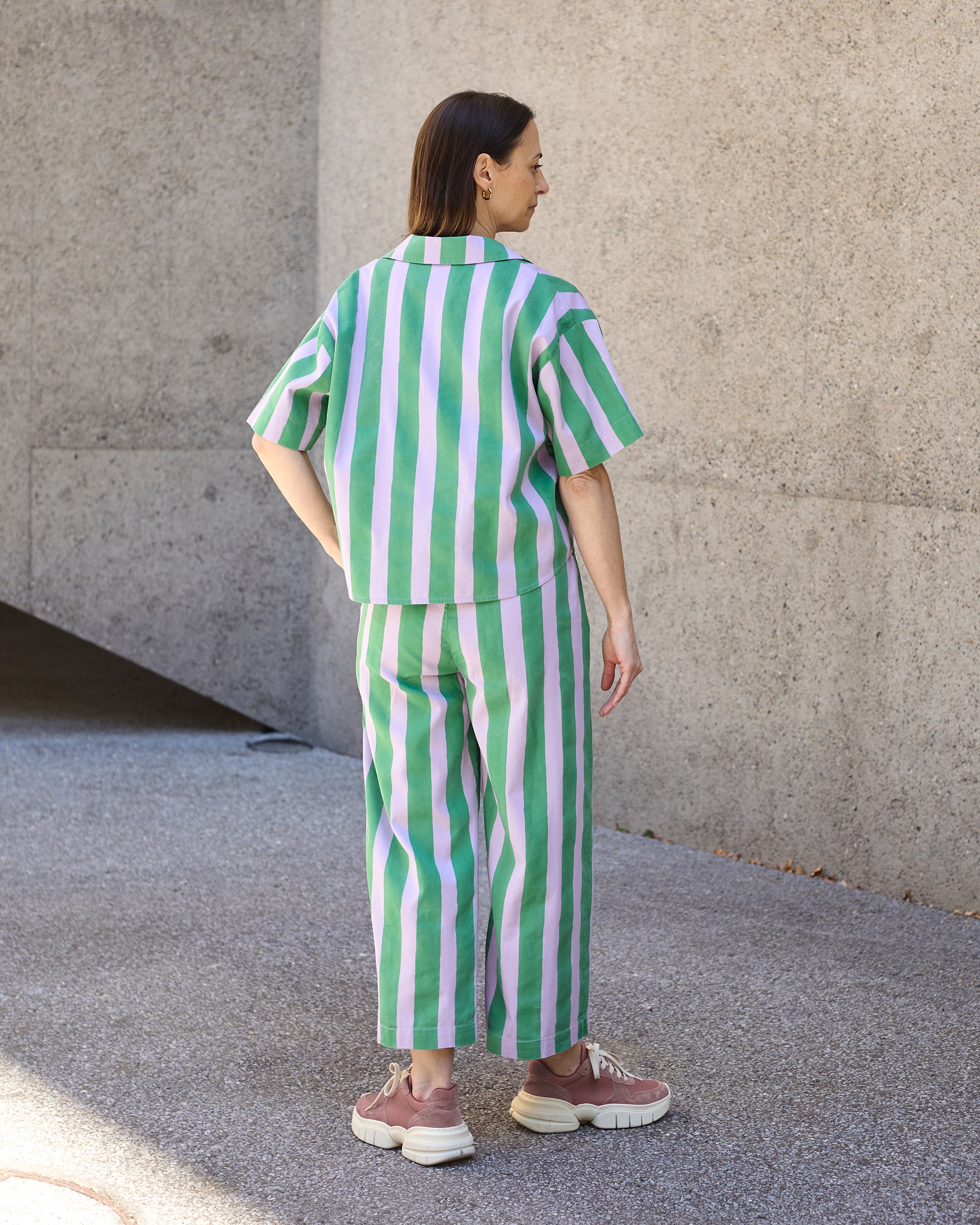 Back view of petite striped blockprint wide-leg trousers in green and lilac stripes.
