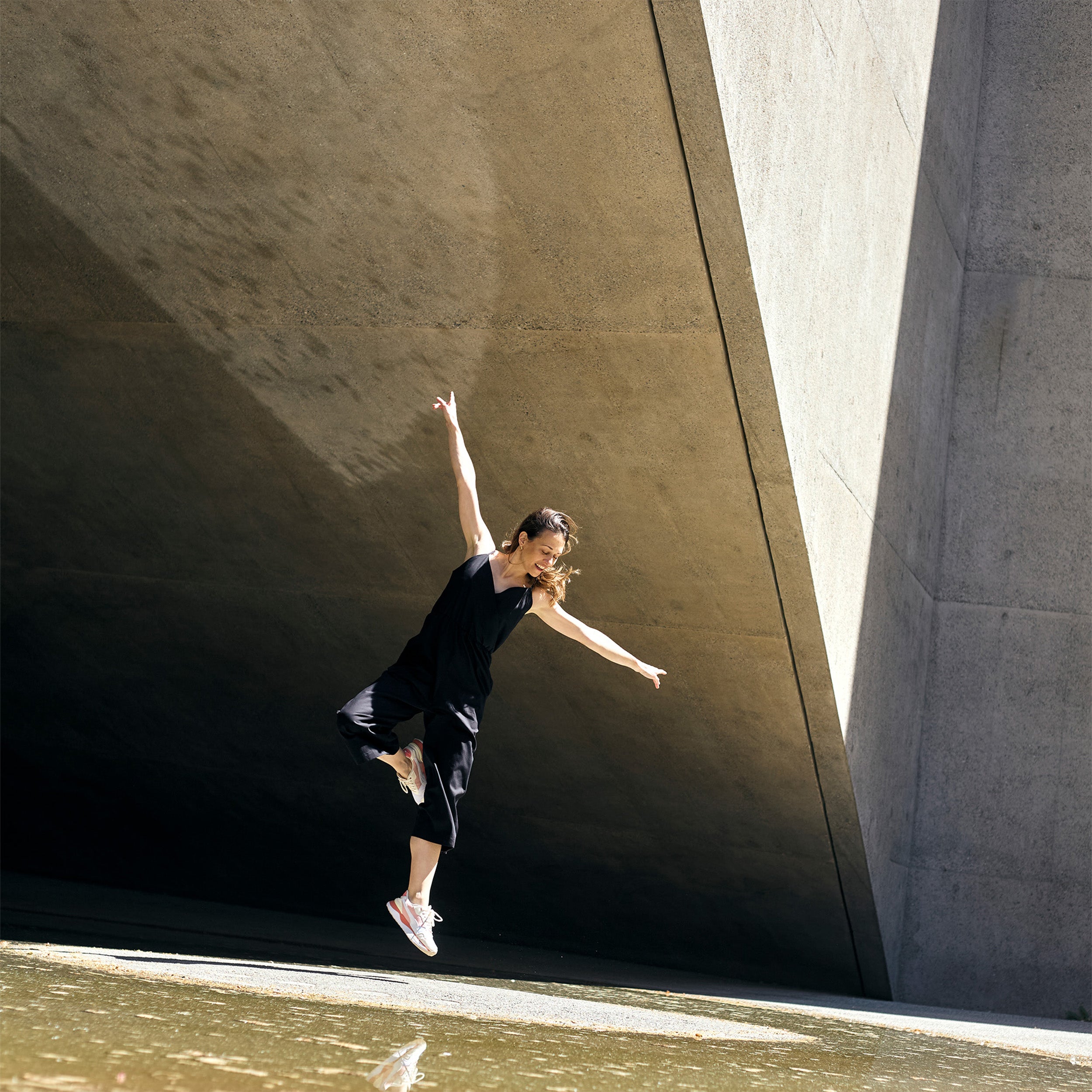 Model wearing petite black wrap jumpsuit captured in motion.